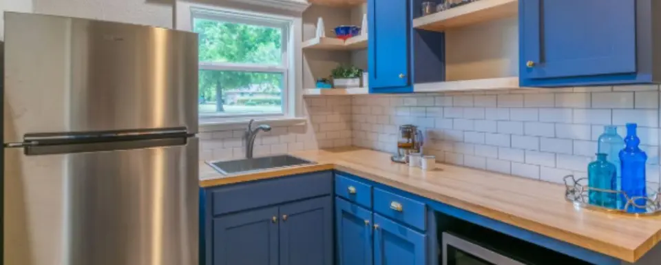 A kitchen with blue cabinets and white walls.