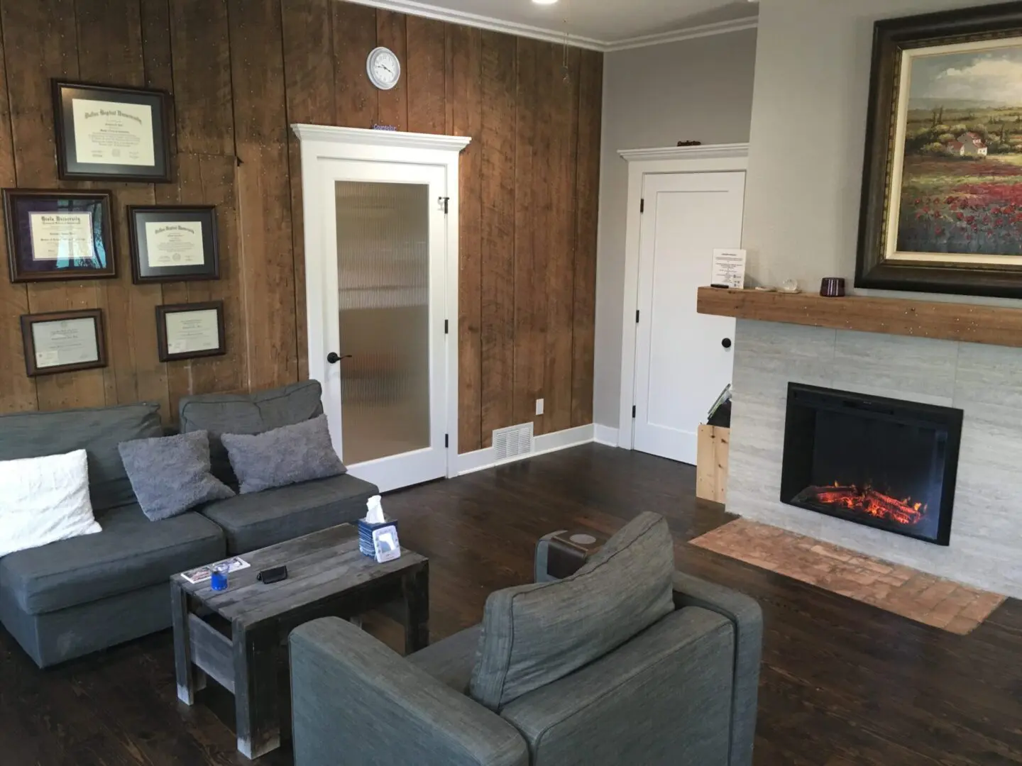 A living room with wood paneled walls and fireplace.